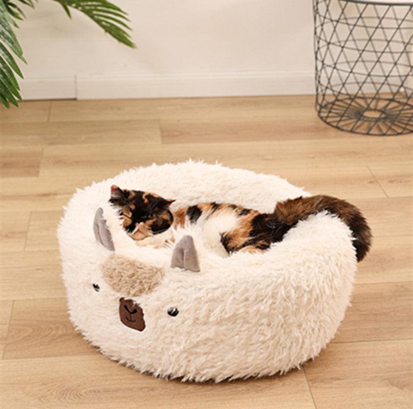 Cat lying on a fluffy white pet bed with a bear design on a wooden floor.