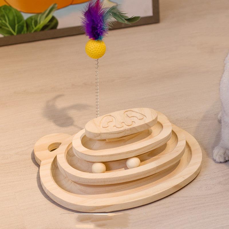 Wooden cat toy with a feather and ball on a beige surface
