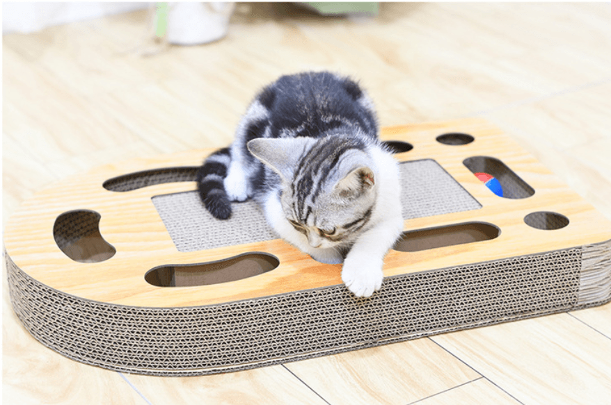 Cat playing with a wooden scratcher on a light wood floor