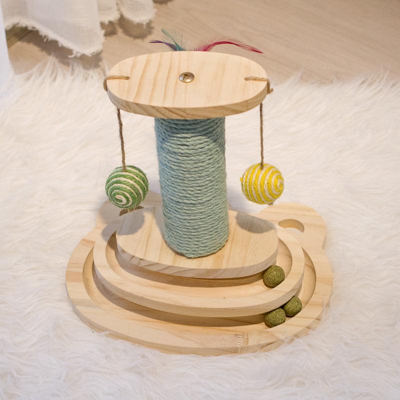 Wooden cat toy with a cylindrical sisal-wrapped post and hanging balls on a textured surface.