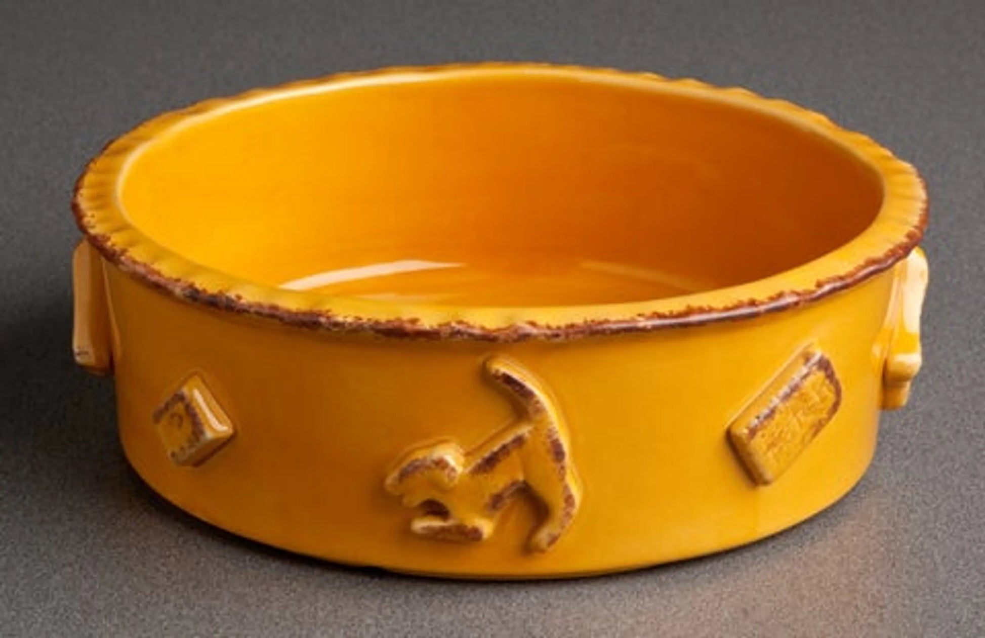 Yellow ceramic bowl with decorative elements on a gray background