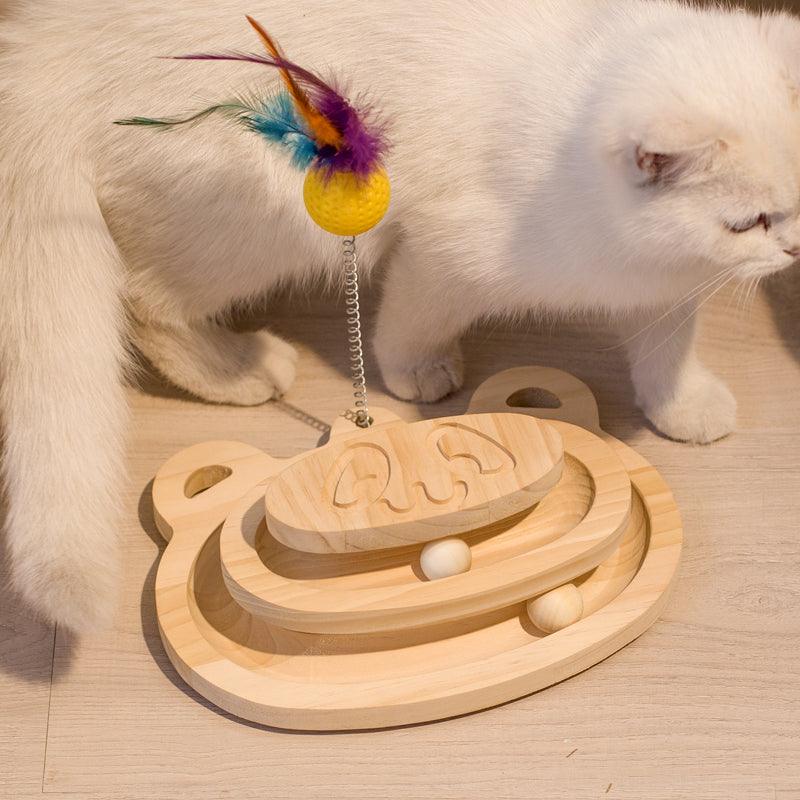 Cat playing with a wooden toy featuring a feathered top