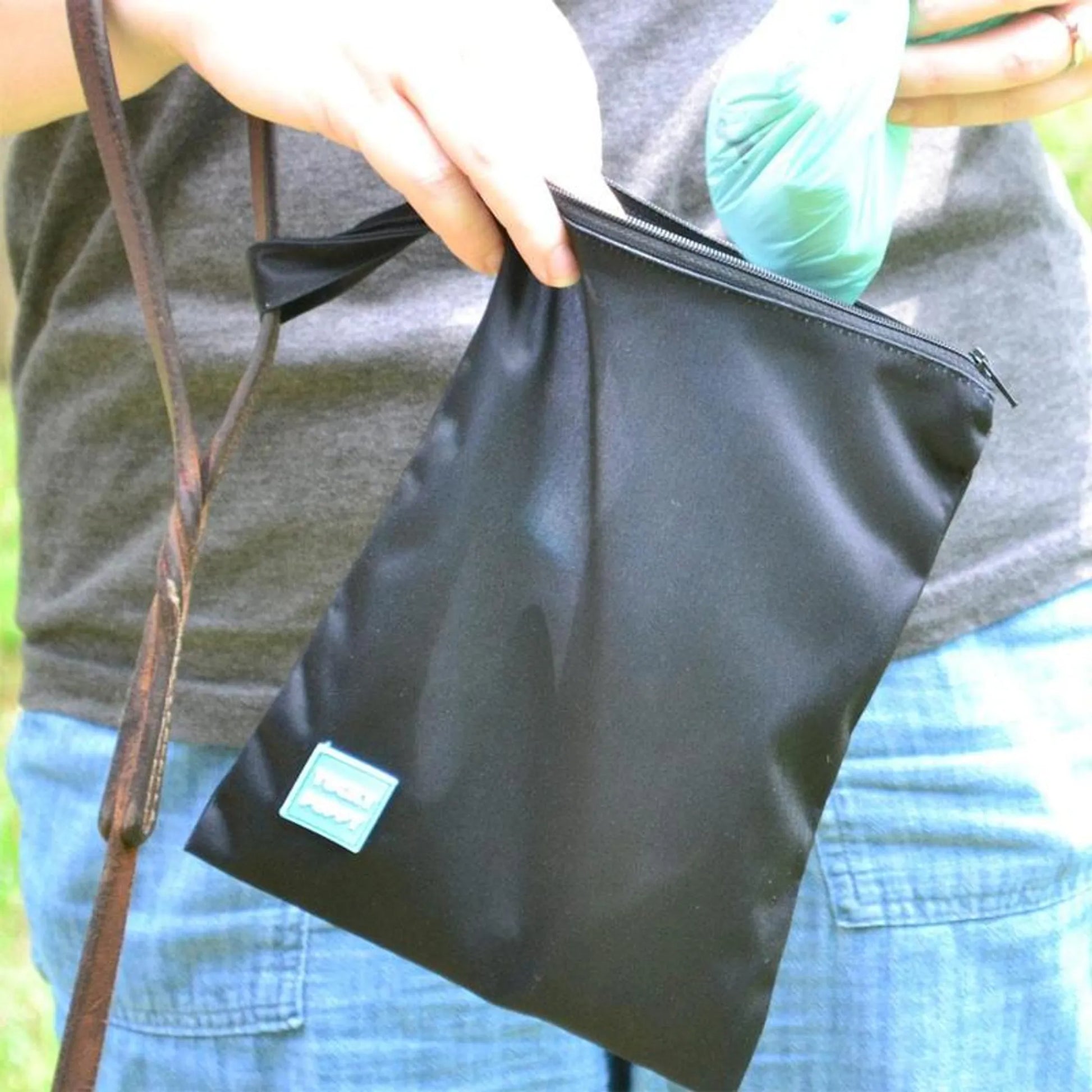 Person holding a black bag with a visible brand label outdoors