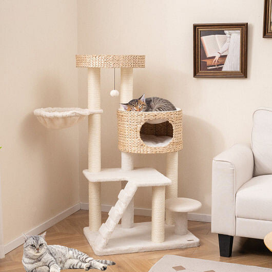 Cat tree with multiple levels and a basket, with two cats in a living room setting.