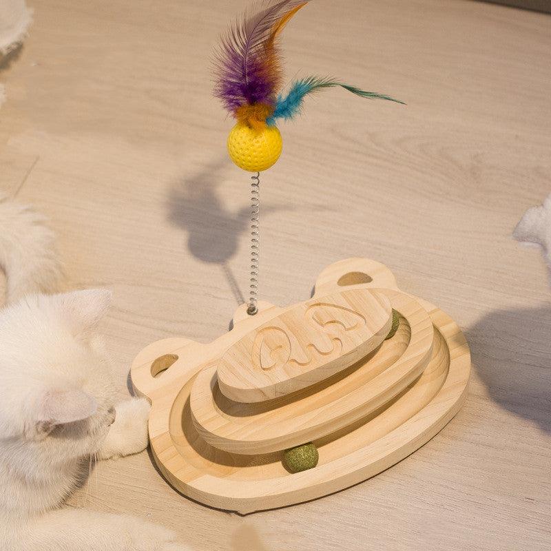 Wooden cat toy with a feather on a light wooden floor.